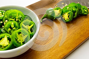 Slicing JalapeÃ±o peppers on a wooden cutting board