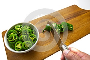 Slicing JalapeÃ±o peppers on a wooden cutting board