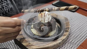 Slicing off sizzling brownie chocolate ice cream from hot plate.