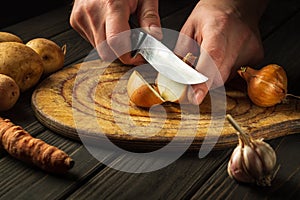 Slicing onions on a cutting board with a knife by the hands of a cook. Working environment in kitchen while preparing lunch chef