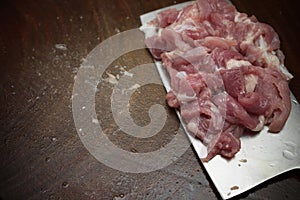Slicing raw pork on wooden chopboard