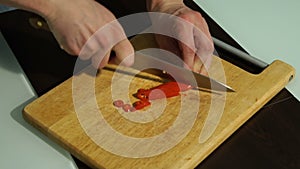 Slicing Red chili pepper. A man cuts pepper on a wooden Board