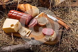 Slicing sandwiches from sausage and hard cheese. Fresh baguette and sausage