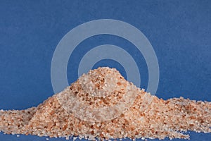 A slide of pink Himalayan table salt on a blue textured background