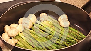 Slide slow motion shot of cooking frozen green asparagus on grill pan