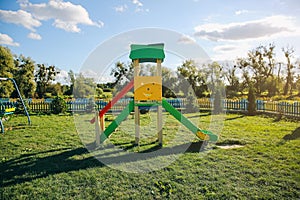 Slide and swings with a wooden house on children playground. Outdoors games for kids. Summer bright day