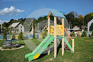 Slide and swings with a wooden house on children playground. Outdoors games for kids. Summer bright day