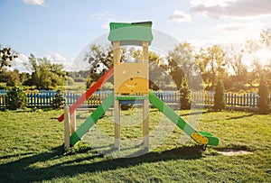 Slide and swings with a wooden house on children playground. Outdoors games for kids. Summer bright day