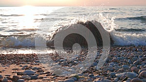 Slider Shot of Small Waves Breaking Over Colorful Boulder Along Beach at Sunset