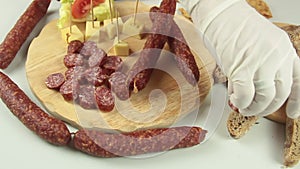 slider view of chefs hands serving a typical South Tyrolean snack plate like Tyrolean smoked sausage on a wooden cutting board