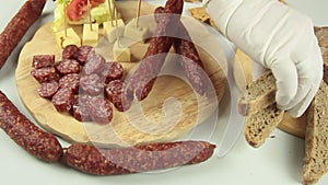 Slider view of chefs hands serving a typical South Tyrolean snack plate like Tyrolean smoked sausage on a wooden cutting board