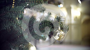 Slider view of small golden mirror ball. New Year`s and abstract blurred shopping mall background with Christmas tree