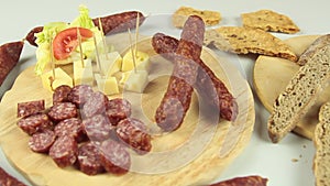 Slider view of a typical South Tyrolean snack plate such as Tyrolean smoked sausage on a wooden cutting board accompanied by