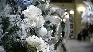 Slider view of white balls and flowers. New Year`s and abstract blurred shopping mall background with Christmas tree