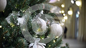 Slider view of white wool balls and lights. New Year`s and abstract blurred shopping mall background with Christmas tree