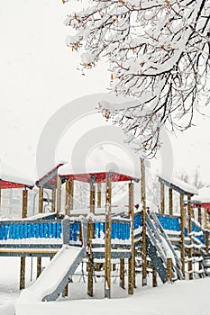 Slides and swings, on the playground, covered with fluffy, white snow.