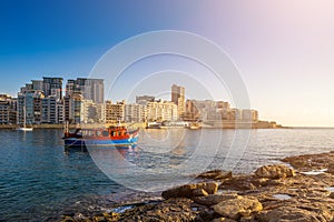 Sliema, Malta - Sunrise with traditional maltese boat and apartments of Tigne point taken from Manoel island