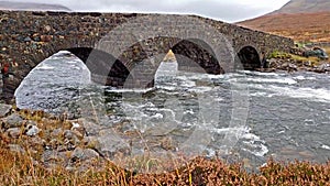 The Sligachan Old stone Bridge over River Sligachan with Beinn Dearg Mhor and Marsco peak of Red Cuillin mountains in