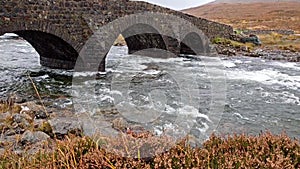 The Sligachan Old stone Bridge over River Sligachan with Beinn Dearg Mhor and Marsco peak of Red Cuillin mountains in