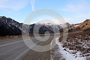 Slight right turn on a paved rural road through a snow-covered mountain valley