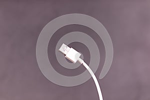 slightly curved to the left white USB cable with a gray wall in the background