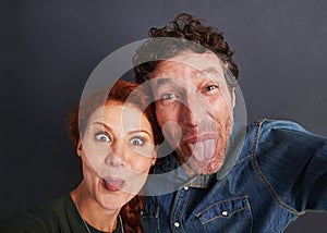 Slightly goofy. Portrait of a happy young couple pulling silly faces for a selfie.