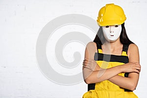 Slightly hunched and with folded arms, a young construction worker stands and waits for a line of white bricks. Stubborn