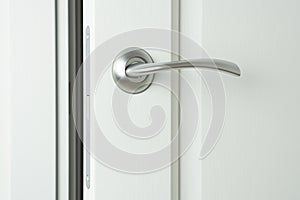 Slightly open white wooden interior door with handle and magnetic locking pawl photo