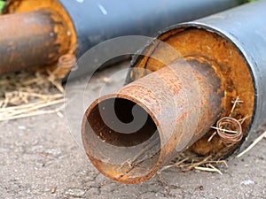 Slightly rusty pipe in thermal insulation, forgotten on asphalt