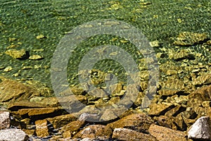 Slightly undulating, purely crystalline water in a mountain lake and submerged granite rocks photo