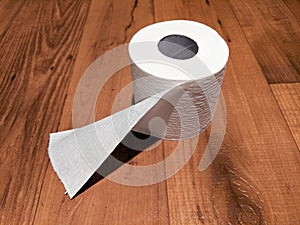 Slightly Unrolled Toilet Paper Roll on Wood Floor