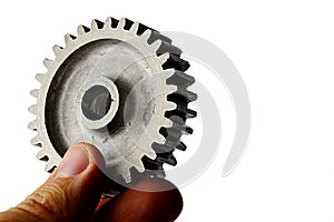 Slightly used alluminium alloy cog wheel from spur gear held in left hand on white background