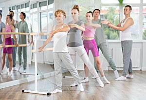 Teenage boys and girls practicing battement tendu position of ballet in dancehall photo