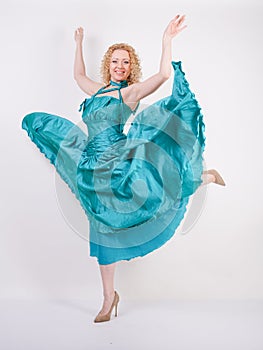 Slim airy girl in flying blue evening dress on white background in Studio