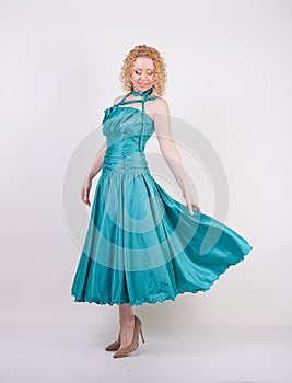 Slim airy girl in flying blue evening dress on white background in Studio