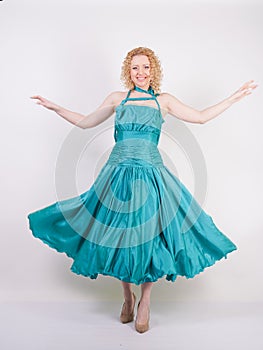 Slim airy girl in flying blue evening dress on white background in Studio