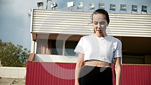 slim asian woman in activewear talks, smiles and laughs on sunny day outdoors