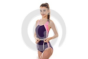 Slim beautiful girl in a sports suit takes the waist measuring tape