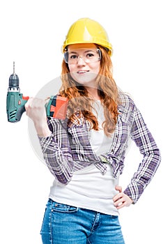 Slim beautiful woman with a drill in protective clothing ready