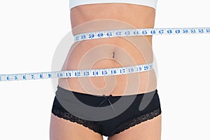 Slim belly surrounded by measuring tape