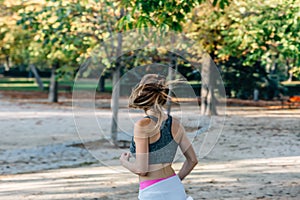 Slim blonde girl jogs and sports in a city park