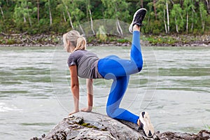 Slim blonde healthy woman doing the donkey kick exercise on all fours arching back straightening leg up. Concept sport, fitness,