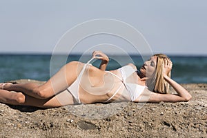 Slim blonde woman lying on sea rocks
