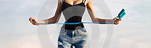 Slim body, jump rope. Girl with perfect waist with a jump rope in hands. Athletic slim woman measuring her waist by