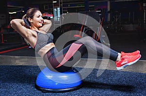 Slim, bodybuilder girl, does the exercises with Ball Balance in the gym.