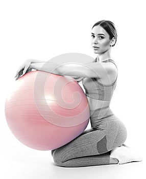Slim, bodybuilder girl in a lilac tracksuit, sitting on a mat with a Pilates ball, cardio workout. Sports concept, fat burning