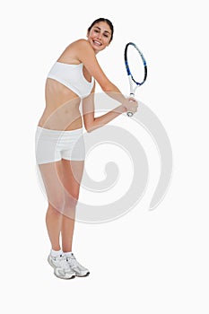 Slim brunette playing tennis in white clothes