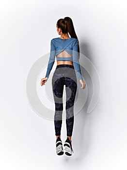 Slim brunette woman running jumping doing  workout exercise in sport wear on gray