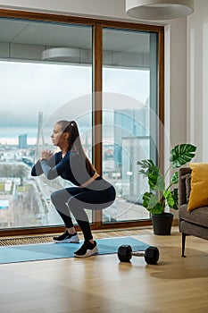 Slim brunette woman in turquoise jumpsuit in squat position