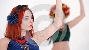 Slim Caucasian woman dancing belly dance with blurred lady performing simultaneously at background. Portrait of